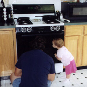 Sara watching dinner in the oven with her dad